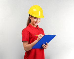 Pretty warehouse worker with clipboard on light background