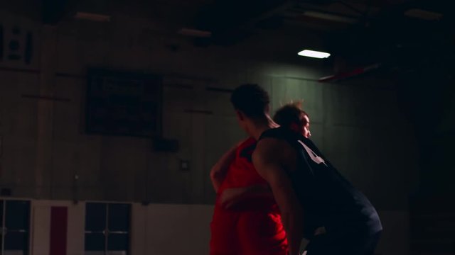 A basketball player being closely defended and then shooting a basket, slow motion
