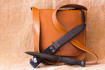 Still life of Military bayonet knife and leather bag on sack bac