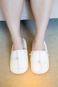 Close up of  woman's white  slippers standing on carpet