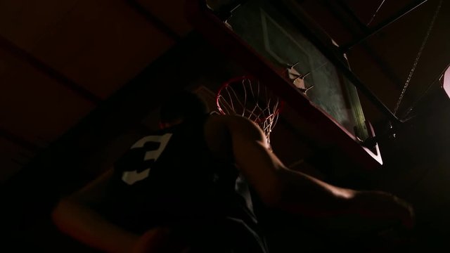 Two basketball players jump up and slam dunk, slow motion, view from below