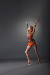 Gymnast girl exercising on grey studio background