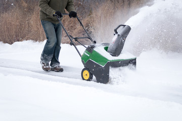 A snowblower in action being pushed during light snowfall