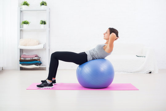 Fitness young woman doing abdominal crunches on fit ball.
