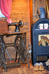 Old sewing machine, and a fireplace, lay next to the firewood. In the fireplace warm