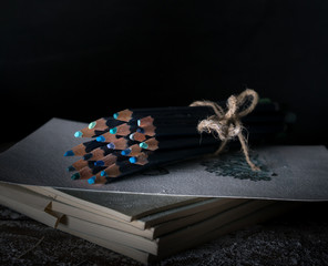 watercolor pencils on the old wooden table. dark background, vintage