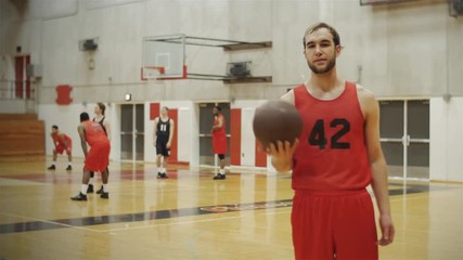 Portrait of a basketball player spinning a ball on his finger, in front of a court