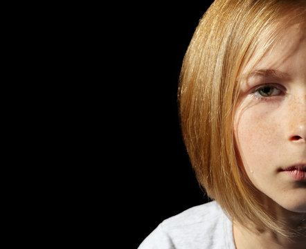 Portrait of sad little girl on black background, closeup