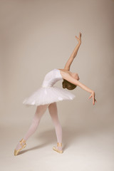 Young beautiful ballerina dancing on light background