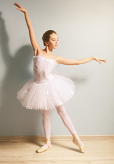 Young beautiful ballerina on wall background