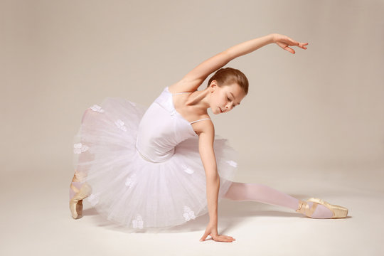 Young beautiful ballerina dancing on light background