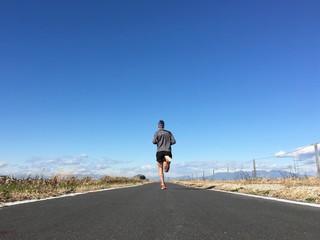 Man running on open country path with winter blue sky