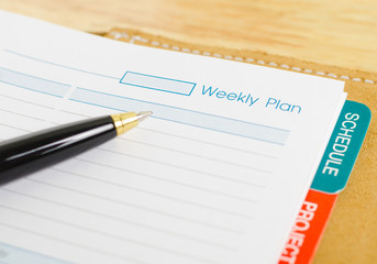 close up shot of daily notebook with pen focus on weekly plan wording business concept