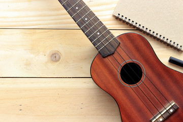 Obraz premium close-up ukulele and notebook on wood background. over light