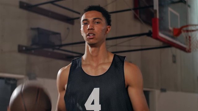 Basketball player tosses a ball back and forth and spins it on his finger