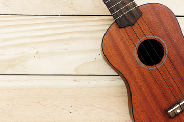 close-up ukulele on wood background. over light