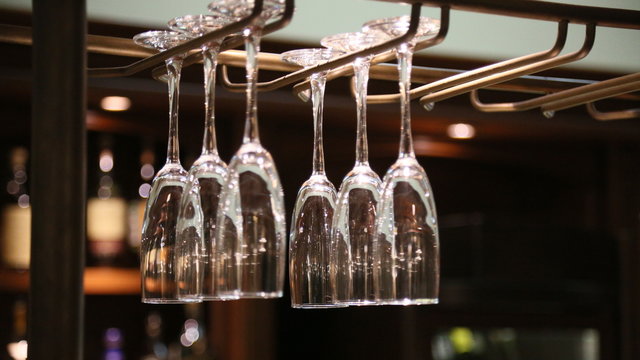 Empty clean wine glasses are hanging above the bar