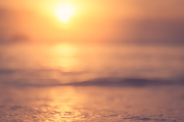 Blur tropical sunset beach with bokeh sun light wave abstract background.