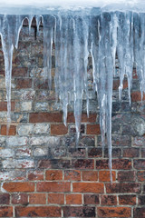 Icicles on a background of an old brick wall 