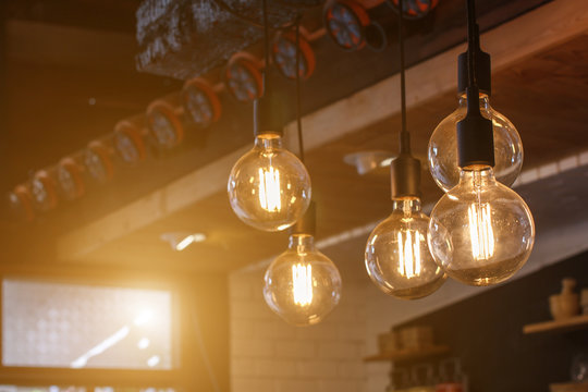 Decorative antique style filament LED light bulbs in restaurant with sunlight background.