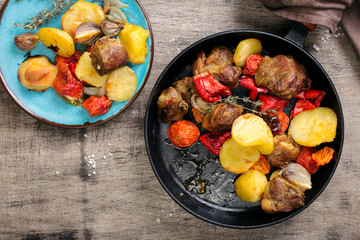 Roasted meat pieces with vegetables in a the pan on wooden table