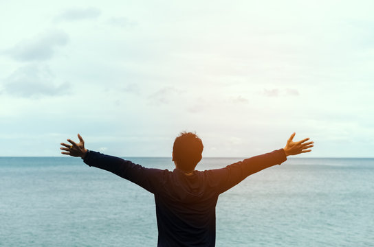Feel good and freedom concept. Copy space of happy man raise hands on beach background.