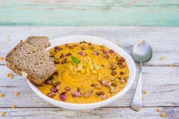 Top view of cream pea soup with bacon and marjoram on wooden rustic background. 