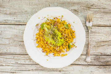 Top view of salad with cooked peas and fresh sprouts with herbs on rustic wooden table. 