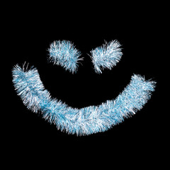 Fototapeta premium Smiling face made of blue tinsel on a black background. Isolated