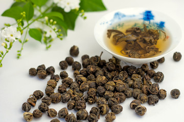 Dry leaves of jasmine green tea scattered and brewed in the chin