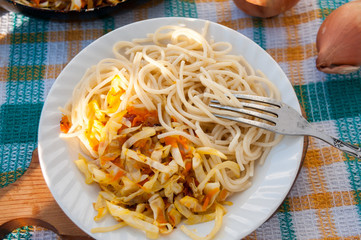 A plate of spaghetti and sauerkraut on a checkered towel  