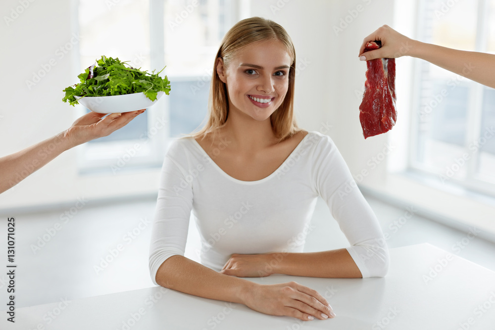 Wall mural healthy beautiful woman choosing between meat and salad