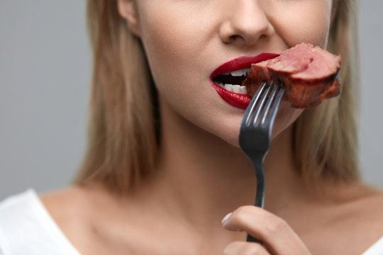 Woman Eating Food. Closeup Of Girl's Face Biting Meat Steak