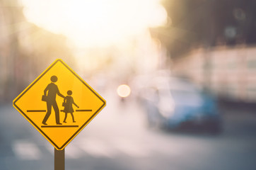 School warning sign on blur traffic road with colorful bokeh light abstract background.