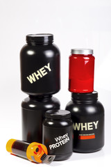 Stock of bodybuilder sports nutrition. Two big black jars with whey protein, one with casein, one...