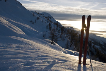 tra i due sci,si vede il tramonto del sole dietro le montagne del monte Bianco 