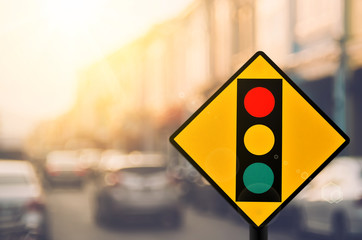 Traffic light warning sign on blur traffic road with colorful bokeh light abstract background.