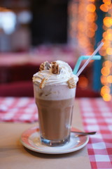 Big cup of coffee with cream and wafers on a table in a restaurant