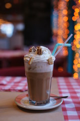 Big cup of coffee with cream and wafers on a table in a restaurant