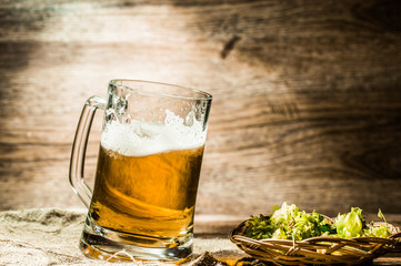 Beer in large mug stands on table next to hop