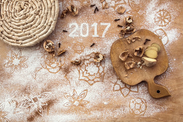 Inscription 2017 written in snow flour on the wooden background, top view. Ingredients for baking biscuit, flour, walnuts