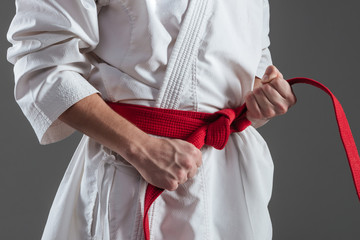 Cropped photo of young sportsman tightening red belt © Drobot Dean