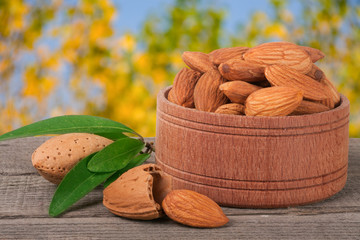 almonds in a bowl on the old wooden board with blurred garden background