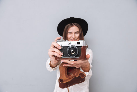 Woman in hat holding retro camera and taking photo