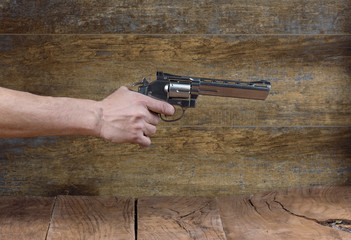 hand with a revolver, a wooden wall