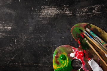 Palette with brushes on a black table