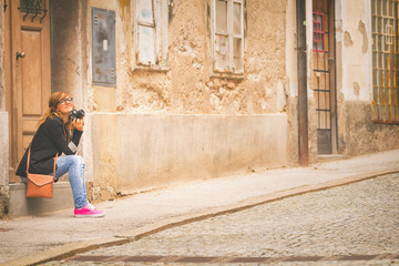 Obraz na płótnie Canvas Girl sitting outdoors and holding a retro camera.