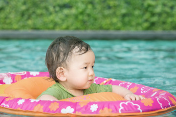 Closeup a asian baby boy sit in a boat for children in the swimming pool background