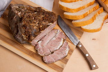 Baked pork with herbs and spice on wooden board and and slices w