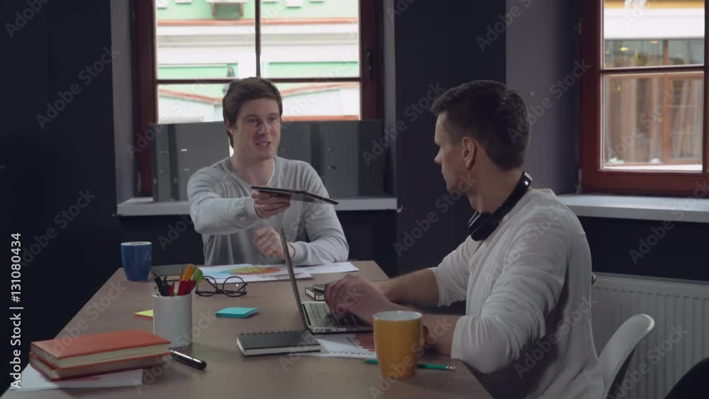 Aufkleber happy colleagues using modern gadgets in the meeting. young professional business men sitting at the